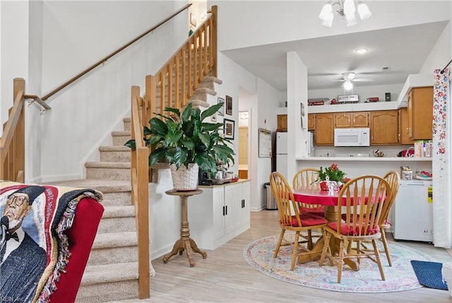 dining room with light wood-style floors, ceiling fan, and stairs