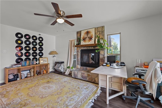 interior space featuring a ceiling fan, a stone fireplace, and wood finished floors