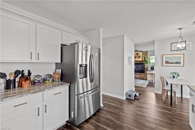 kitchen featuring white cabinets, dark wood-style flooring, light stone counters, stainless steel fridge, and baseboards