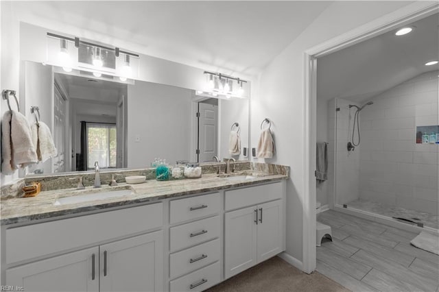 bathroom featuring double vanity, a sink, recessed lighting, and tiled shower