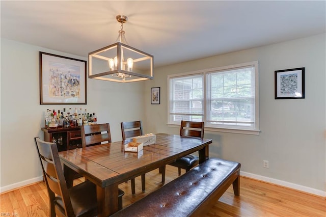 dining area with an inviting chandelier, light wood-style floors, and baseboards