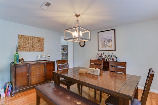 dining area featuring an inviting chandelier, light wood-style floors, and visible vents