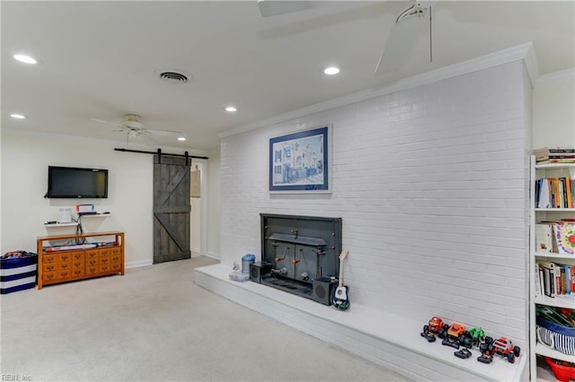 living room featuring visible vents, crown molding, carpet flooring, a barn door, and a ceiling fan