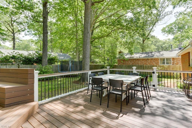 wooden terrace featuring a lawn, a fenced backyard, and outdoor dining space