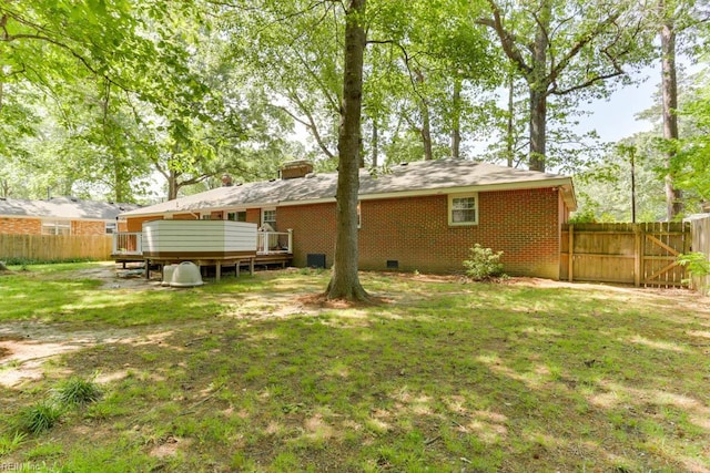 rear view of house featuring a lawn, a deck, fence, and brick siding