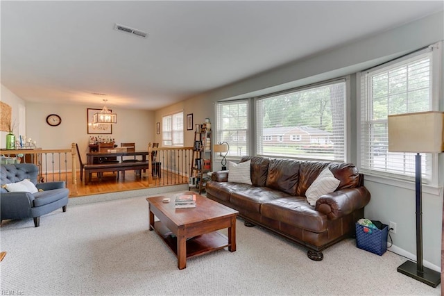 carpeted living room with visible vents and a chandelier