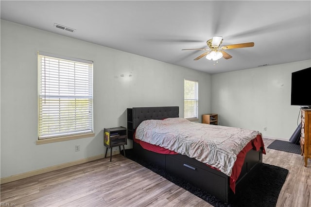 bedroom with baseboards, ceiling fan, wood finished floors, and visible vents