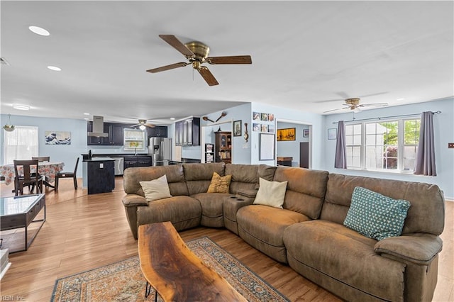 living room with a ceiling fan, recessed lighting, and light wood-type flooring