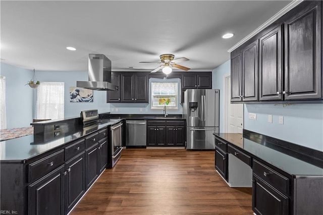 kitchen featuring dark countertops, appliances with stainless steel finishes, range hood, a sink, and a peninsula