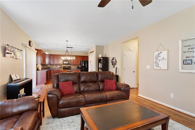 13095 Lighthouse Ln, Carrollton, VA 23314 - living area featuring ceiling fan, light wood-type flooring, baseboards, and a chandelier