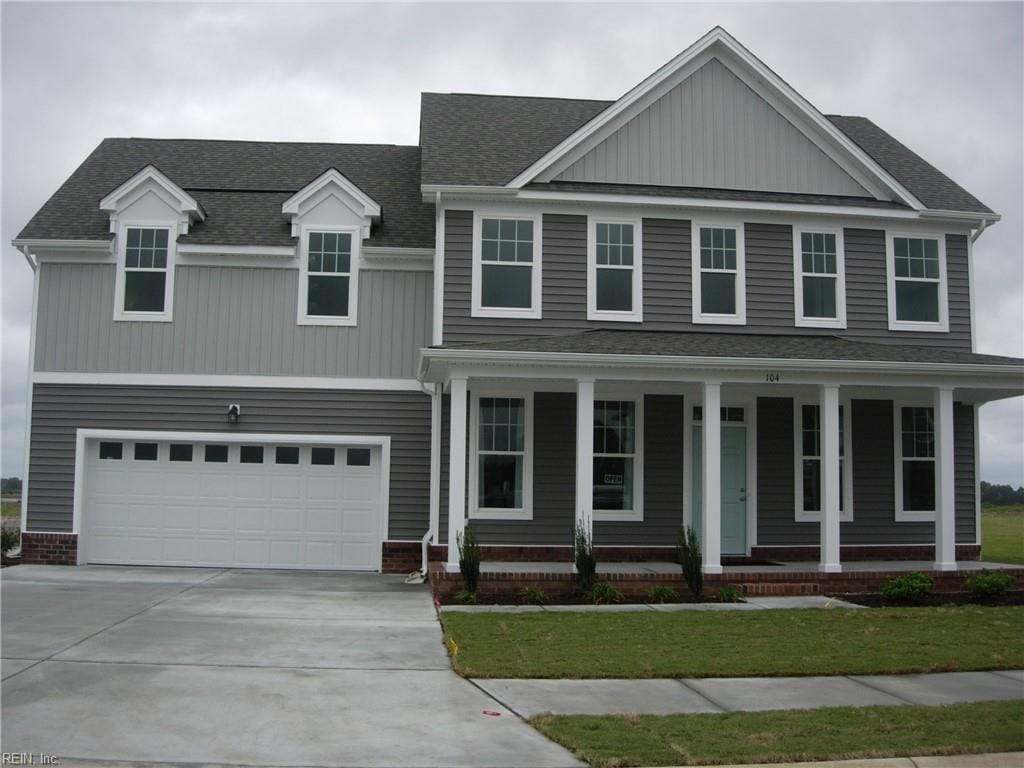 craftsman-style home featuring an attached garage, a shingled roof, a front yard, concrete driveway, and covered porch