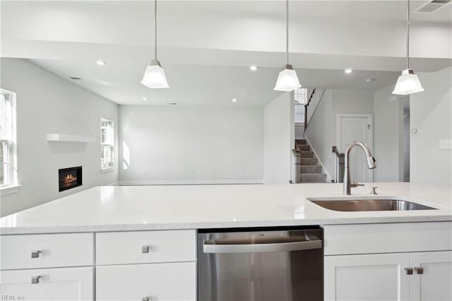 kitchen with stainless steel dishwasher, a sink, white cabinets, open floor plan, and recessed lighting