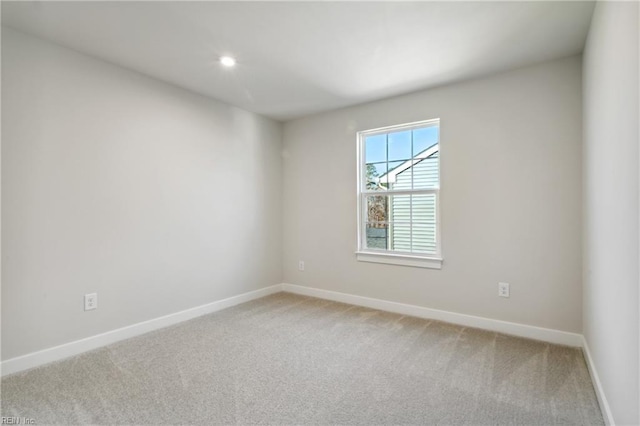 spare room featuring baseboards, light carpet, and recessed lighting