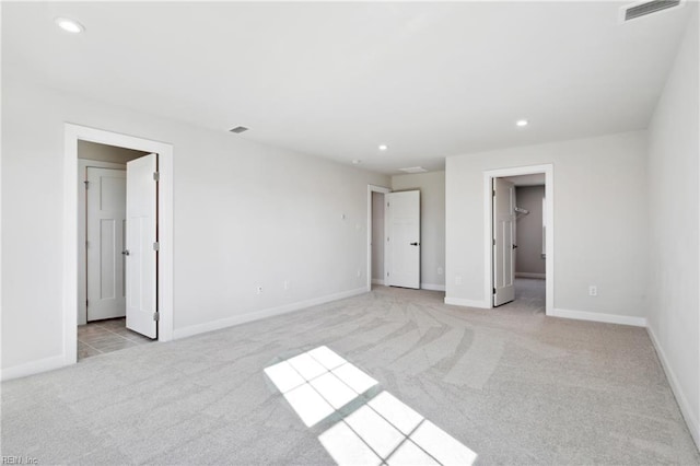unfurnished bedroom featuring visible vents, recessed lighting, a walk in closet, and light carpet