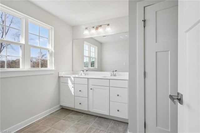 bathroom featuring baseboards, a sink, and double vanity