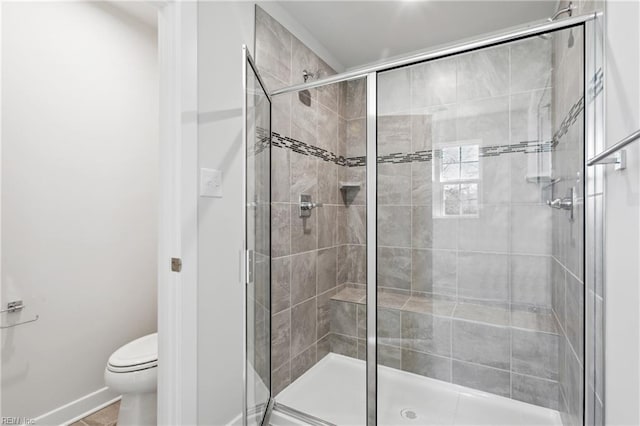 bathroom featuring baseboards, a stall shower, and toilet