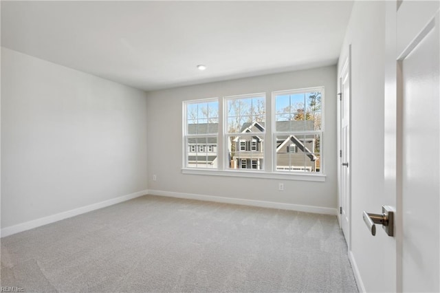 empty room featuring baseboards and light carpet