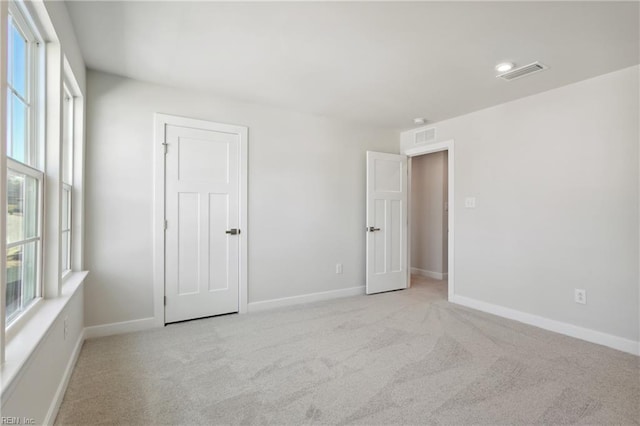 unfurnished room featuring light colored carpet, baseboards, and visible vents