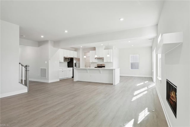 unfurnished living room with recessed lighting, baseboards, visible vents, and light wood finished floors