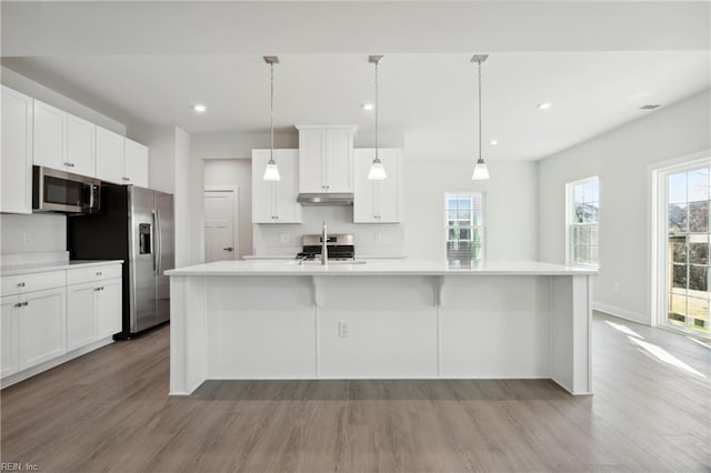 kitchen with light countertops, white cabinetry, appliances with stainless steel finishes, and wood finished floors
