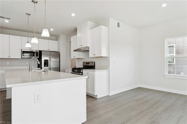 kitchen with light countertops, appliances with stainless steel finishes, under cabinet range hood, and visible vents