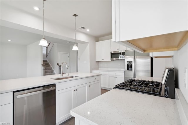 kitchen featuring appliances with stainless steel finishes, hanging light fixtures, a sink, white cabinetry, and visible vents