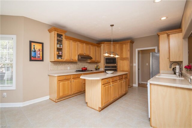 kitchen with backsplash, appliances with stainless steel finishes, a sink, light countertops, and under cabinet range hood