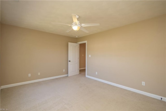 spare room with baseboards, ceiling fan, and light carpet