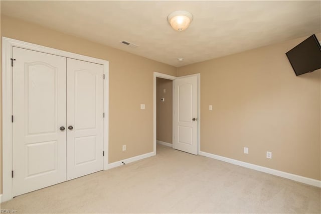 unfurnished bedroom with baseboards, visible vents, a closet, and light colored carpet