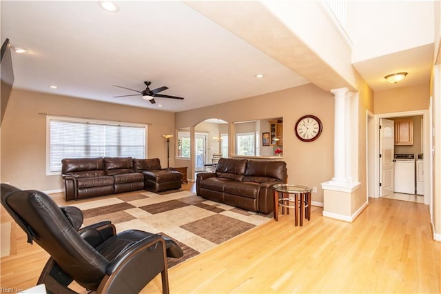 living area with arched walkways, decorative columns, a ceiling fan, and light wood finished floors