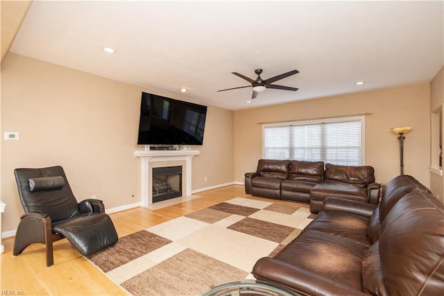 living room with ceiling fan, a fireplace with flush hearth, baseboards, light wood finished floors, and recessed lighting