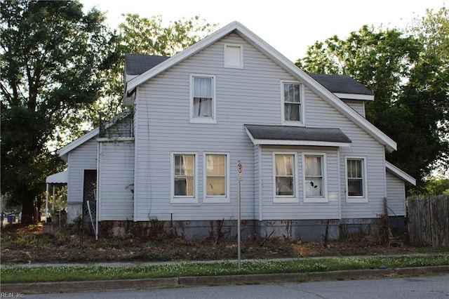 view of side of home with fence and roof with shingles
