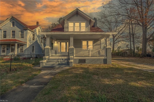 bungalow with a porch, a front lawn, and fence