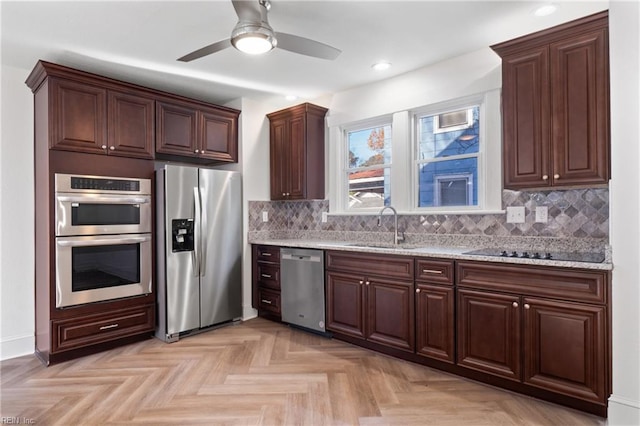 kitchen featuring a ceiling fan, tasteful backsplash, a sink, light stone counters, and stainless steel appliances