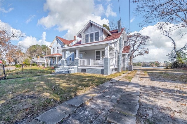 view of front of home featuring fence, a front lawn, a chimney, covered porch, and driveway