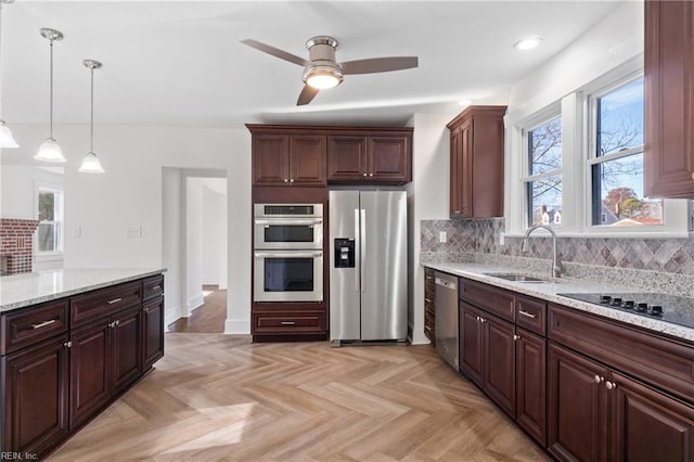 kitchen featuring a sink, a ceiling fan, stainless steel appliances, and backsplash