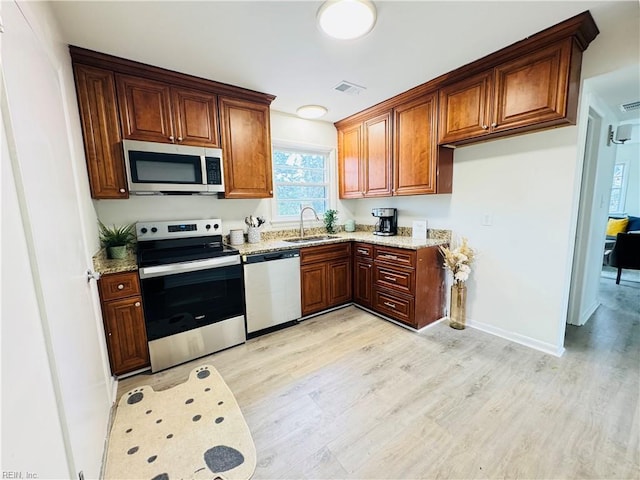 529 Stockton St, Hampton, VA 23669 - kitchen featuring stainless steel appliances, a sink, light wood-style floors, light stone counters, and brown cabinetry