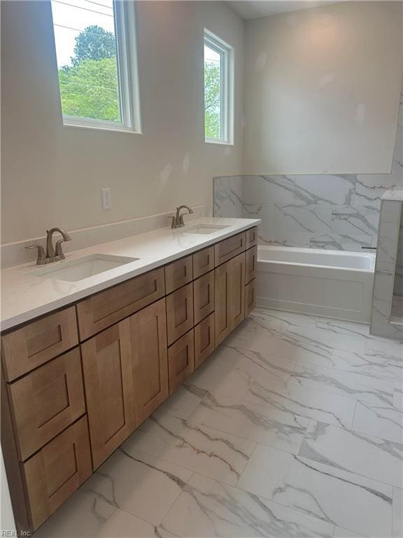 full bathroom featuring a garden tub, a sink, and marble finish floor