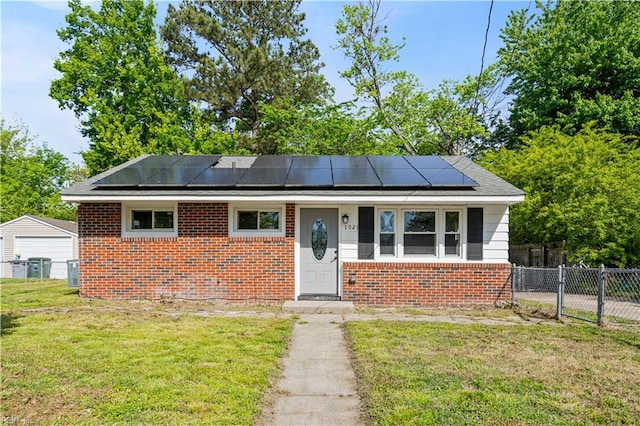 bungalow with brick siding, fence, a front yard, and solar panels