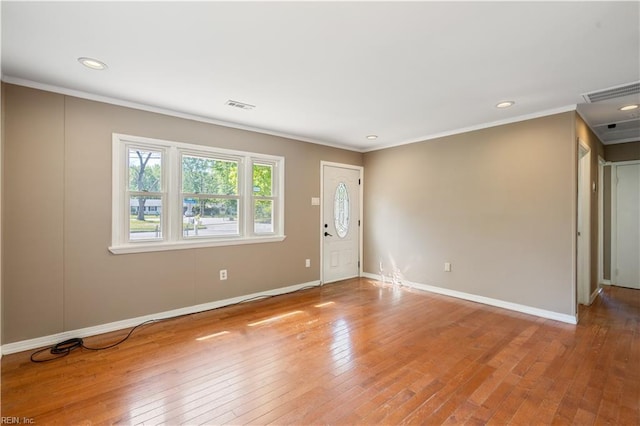 unfurnished room with visible vents, wood-type flooring, crown molding, and baseboards