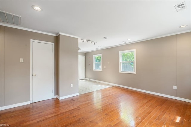 empty room with crown molding, visible vents, and light wood-style floors