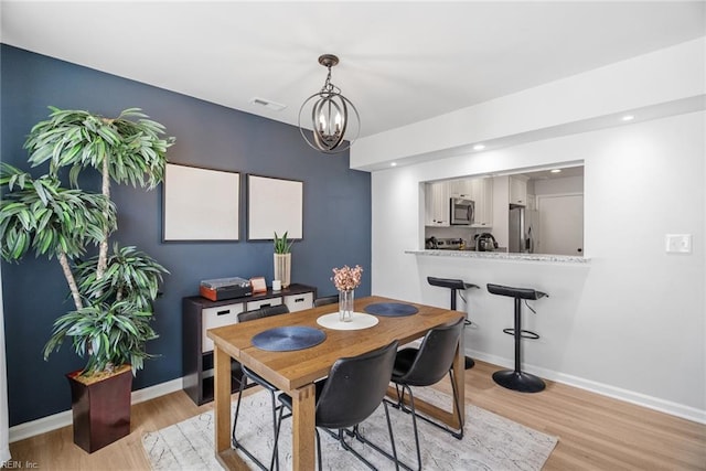 dining area featuring an inviting chandelier, baseboards, light wood finished floors, and visible vents
