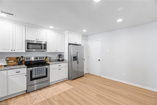 kitchen featuring visible vents, light stone countertops, white cabinets, light wood finished floors, and appliances with stainless steel finishes