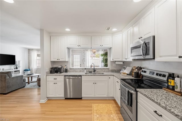 kitchen featuring stainless steel appliances, plenty of natural light, a sink, and light wood-style flooring