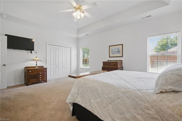 bedroom featuring visible vents, carpet floors, a closet, baseboards, and a tray ceiling