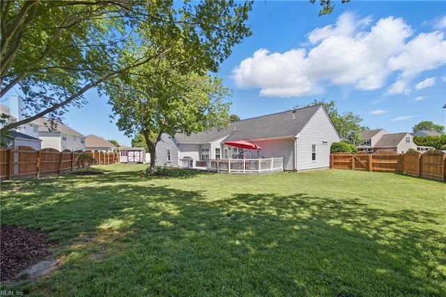view of yard featuring a storage shed, an outbuilding, a fenced backyard, and a deck