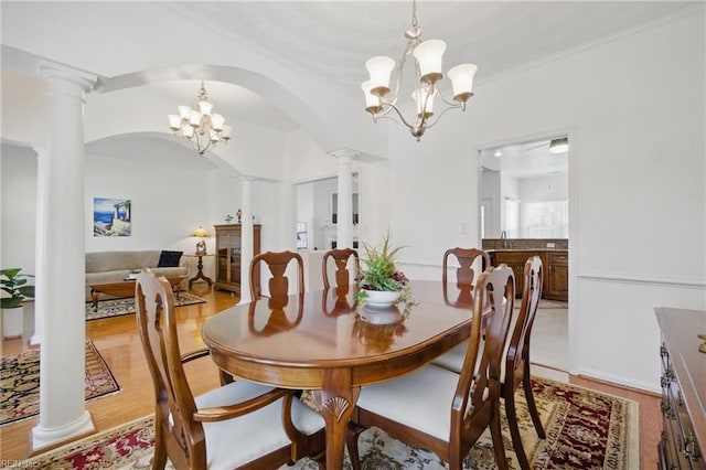 dining room with an inviting chandelier, ornate columns, and light wood-type flooring
