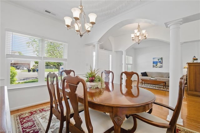 dining space featuring an inviting chandelier, a healthy amount of sunlight, ornate columns, and visible vents