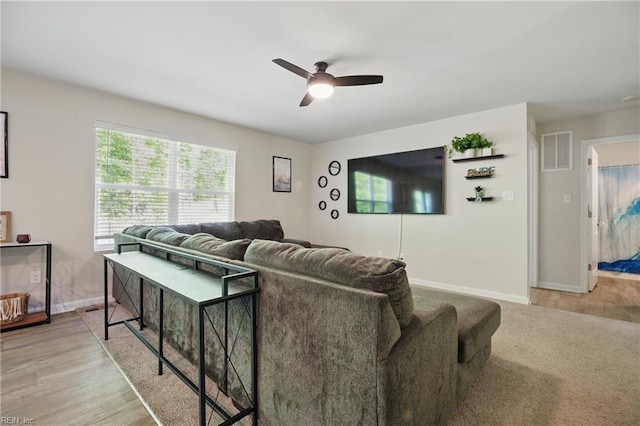 living room with light wood-style floors, baseboards, a ceiling fan, and visible vents
