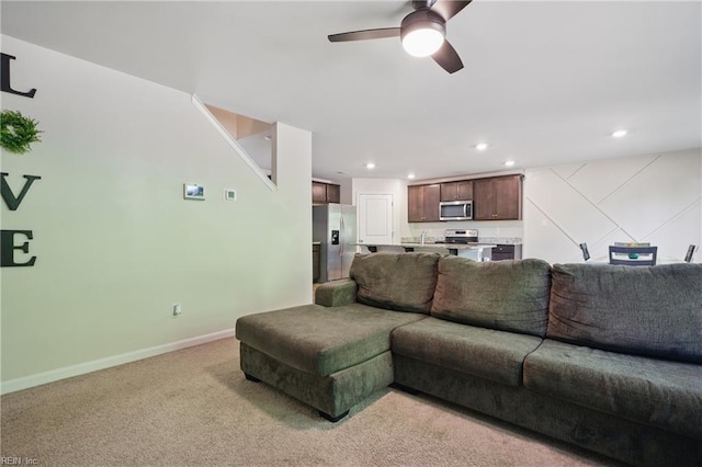 living room featuring a ceiling fan, baseboards, recessed lighting, and light carpet